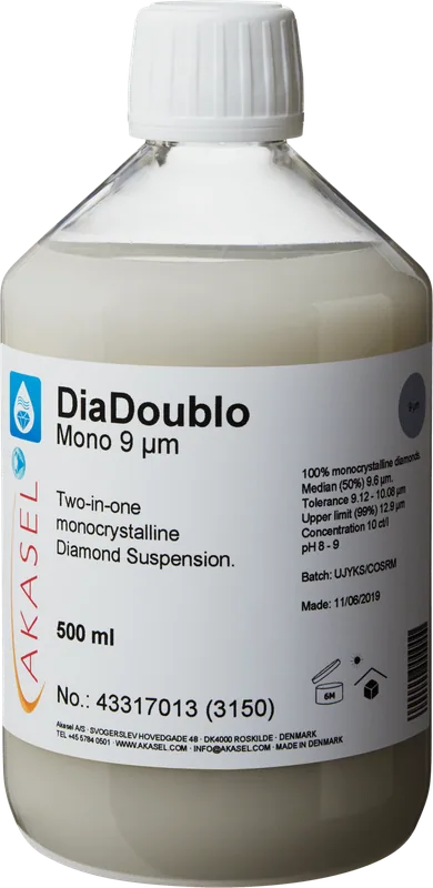 Akasel DiaDoublo Mono 9 µm: En 500 ml plastflaska med vit skruvkork, innehållande en ljus, mjölkvit monokristallin diamantsuspension. Etiketten visar produktnamnet “DiaDoublo Mono 9 µm” tillsammans med beskrivningen “Two-in-one monocrystalline Diamond Suspension.” Ytterligare detaljer inkluderar: “100% monocrystalline diamonds,” “Median (50%) 9.6 µm,” “Tolerance 9.12 – 10.08 µm,” “Upper limit (99%) 12.9 µm,” och en koncentration på “10 ct/l.” Symboler på etiketten anger lagringsförhållanden och hållbarhet.