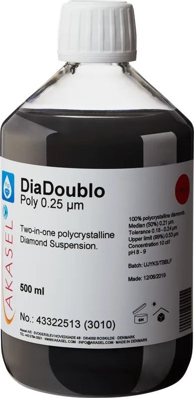 Akasel DiaDoublo Poly 0.25 µm: En 500 ml plastflaska med vit skruvkork, innehållande en svart vätska. Etiketten visar produktnamnet “DiaDoublo Poly 0.25 µm” och beskriver det som en “Two-in-one polycrystalline Diamond Suspension.” Ytterligare detaljer inkluderar: “100% polycrystalline diamonds,” “Median (50%) 0.21 µm,” “Tolerance 0.18 – 0.24 µm,” “Upper limit (99%) 0.53 µm,” en diamantkoncentration på 10 ct/l, och ett pH-värde på 8 – 9. Ett batchnummerfält och produktionsdatum är också angivna på etiketten.