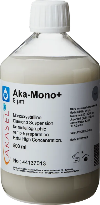 Akasel Aka-Mono+ 9 µm: 500 ml flaska med vit skruvkork, innehållande en ljus, mjölkvit monokristallin diamantsuspension, speciellt utvecklad för metallografisk provberedning. Etiketten innehåller information såsom “Diamond concentration of 40 ct/l,” “Median (50%) 9.6 µm,” “Tolerance 9.12 – 10.08 µm,” och “Upper limit (99%) 12.9 µm.” Suspensionen är lämplig för alla material utom vattenkänsliga och möjliggör exakt justering av förhållandet mellan suspension och smörjmedel.
